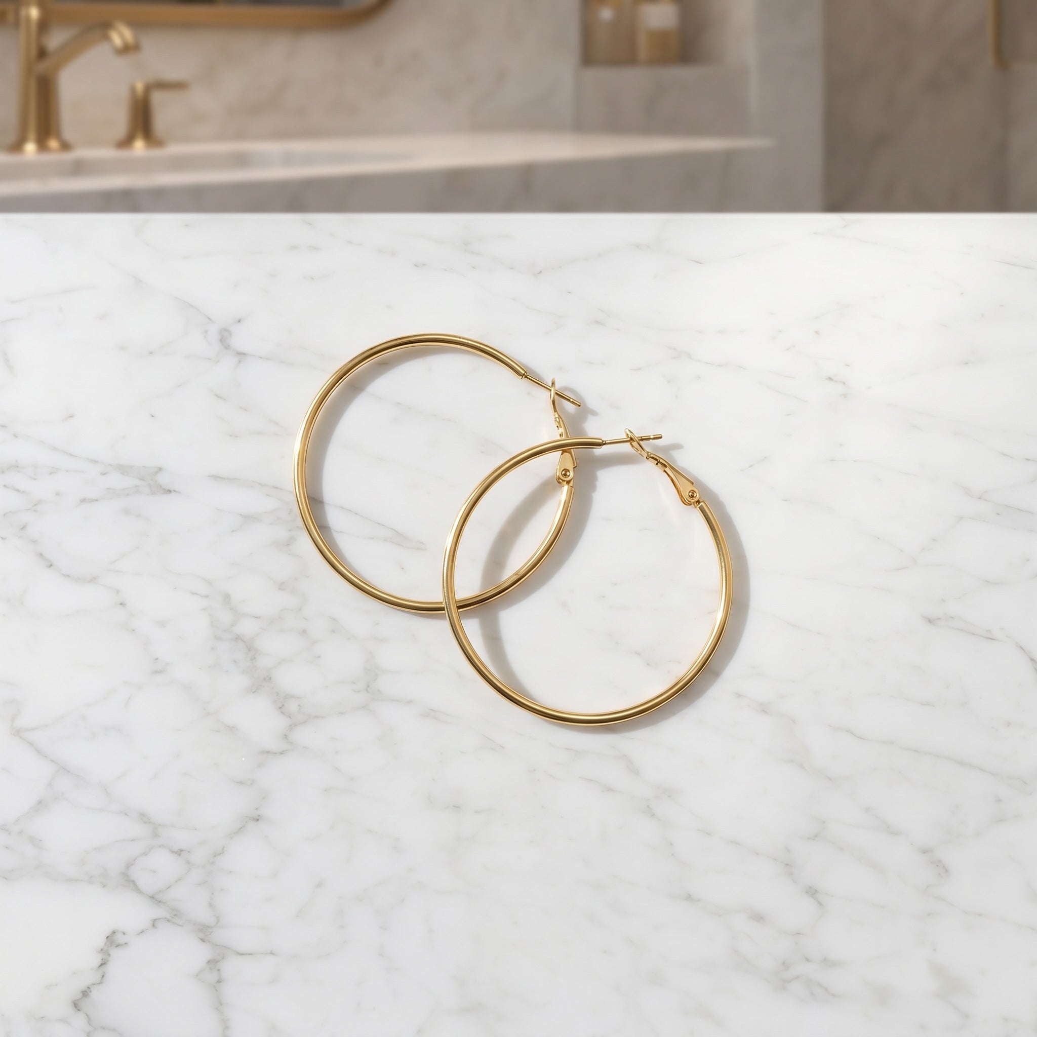 Gold hoop earrings on a marble surface