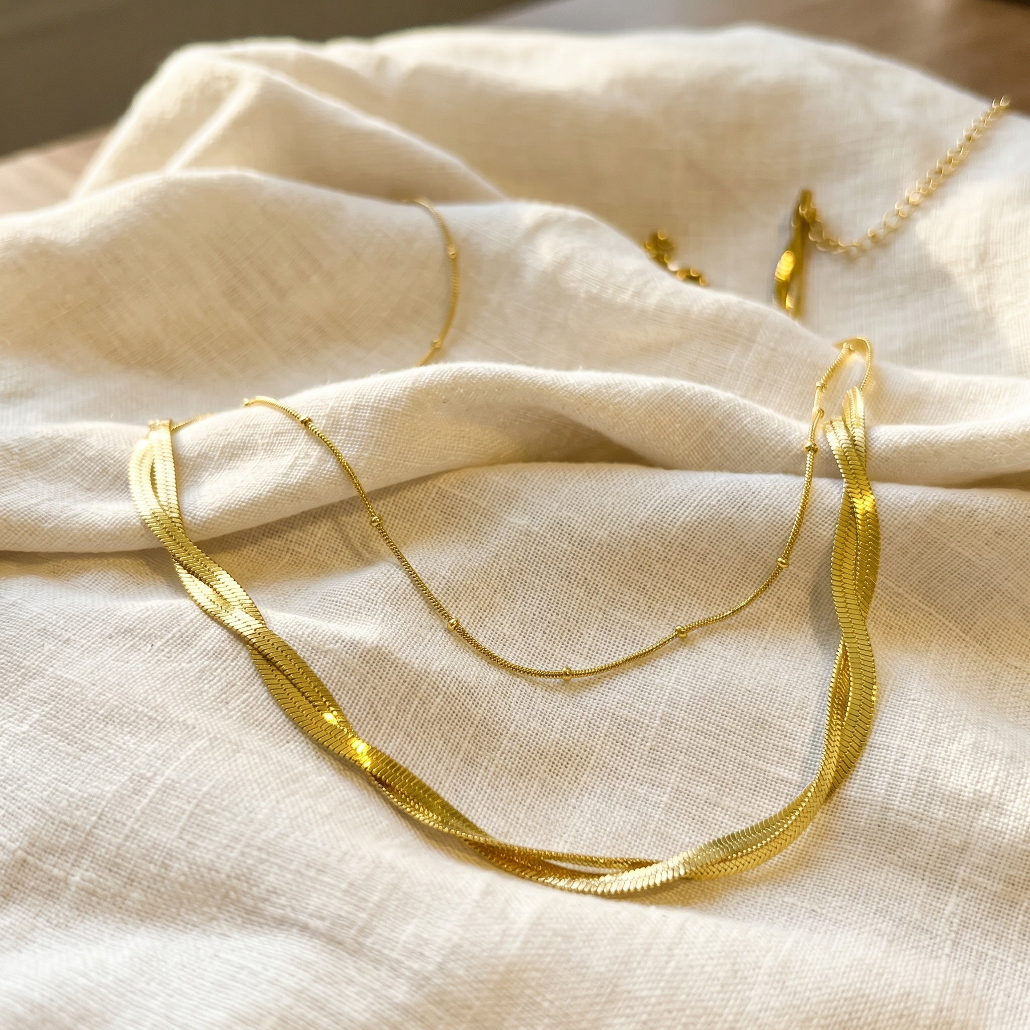 Gold necklaces on a beige fabric surface